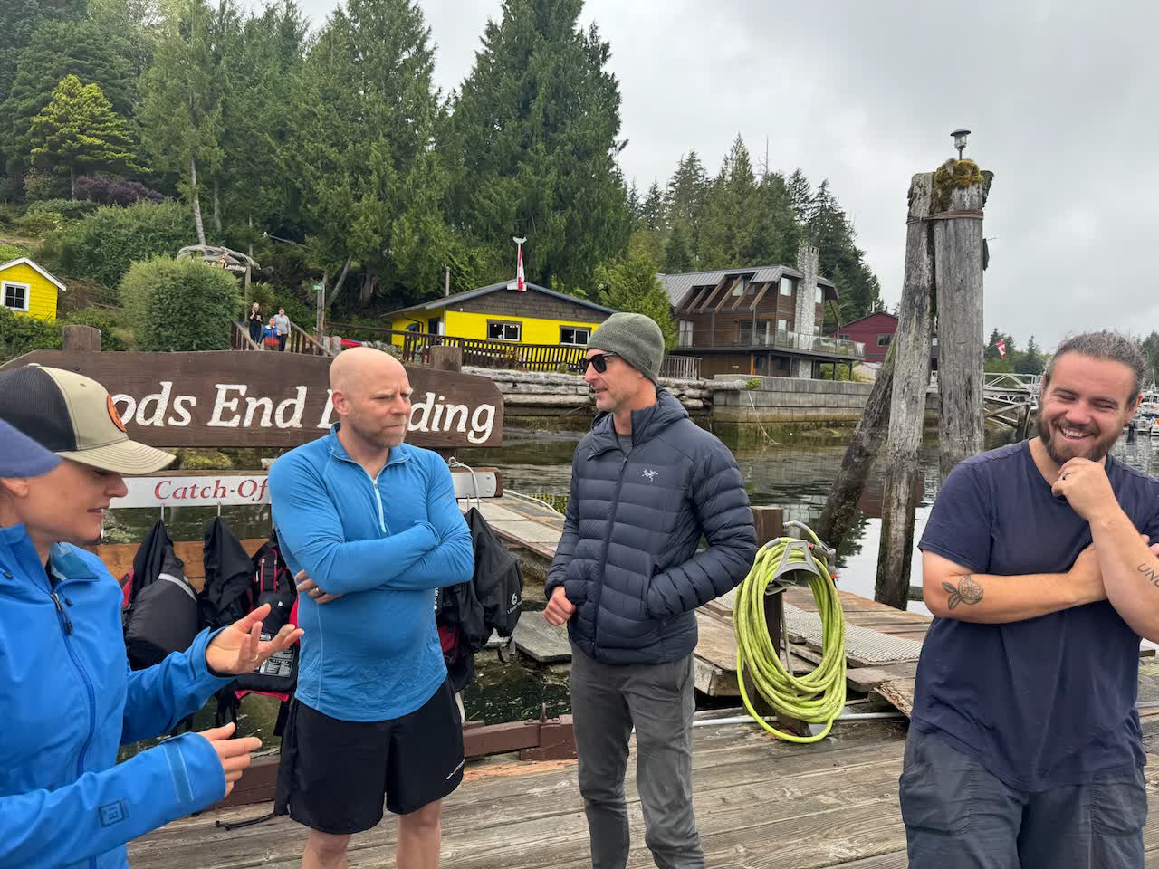 Group of paddlers chatting on the dock at Woods End Landing with the yellow building in the background
